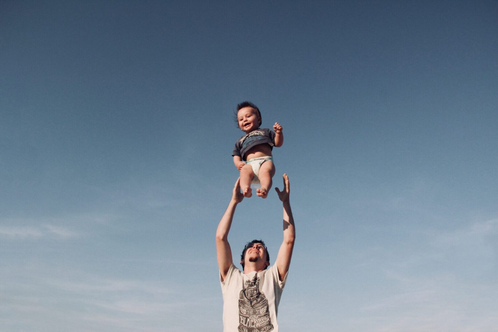 Man in Raising Baby Under Blue Sky